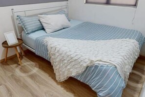 A bed with a white and blue striped bedspread, a white pillow, and a white textured blanket. - Barakah Sufi Home Stay Apartment Cameron (Tanah Rata)