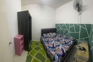 A bedroom with a bed, a wardrobe, a fan, and a green rug. - Barakah Sufi Home Stay Apartment Cameron (Tanah Rata)