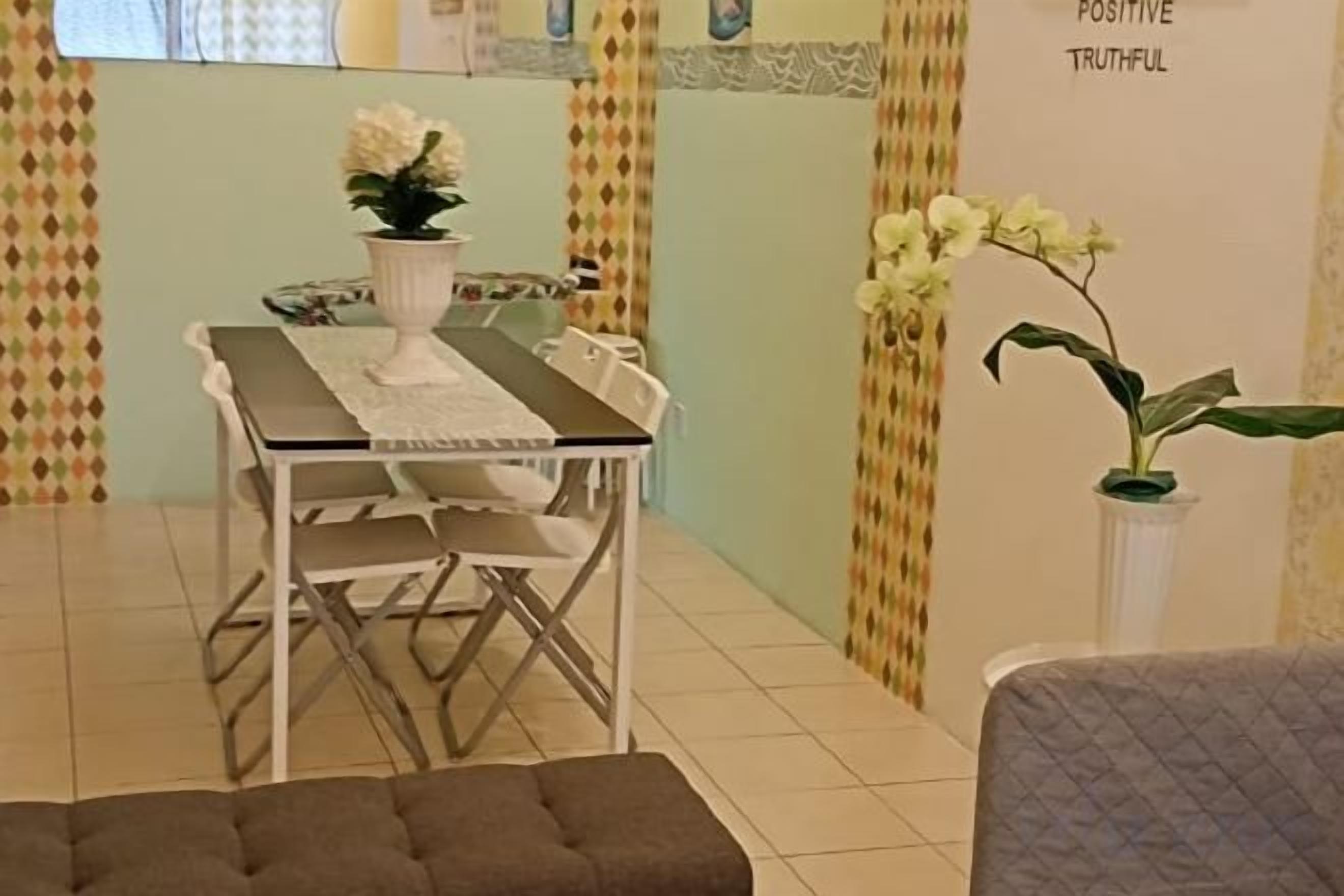 Uma área de refeições com mesa, cadeiras e plantas em vasos.
