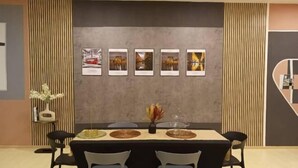 Un comedor con una mesa dispuesta para cuatro personas, flanqueada por listones de madera verticales y cuadros en la pared.