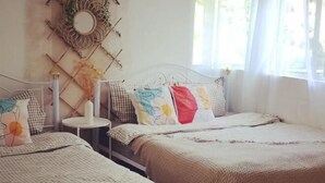 A room with two beds, a round mirror, and a small table with a vase. - Barakah Sufi Home Stay Apartment Cameron (Tanah Rata)