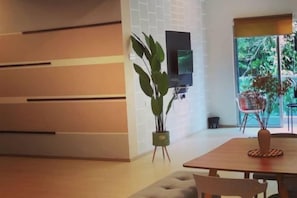 A modern living room with a wooden dining table, a sofa, and a potted plant. - Barakah Sufi Home Stay Apartment Cameron (Tanah Rata)