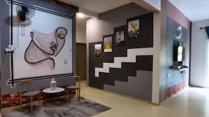 Un interior moderno con una escalera, arte abstracto en la pared y una pequeña zona de estar con una mesa y sillas.