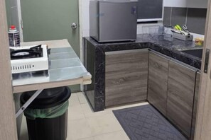 A compact kitchen with a countertop, a trash bin, and a refrigerator. - Barakah Sufi Home Stay Apartment Cameron (Tanah Rata)