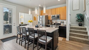 A modern kitchen with a central island, stainless steel appliances, and wooden cabinets.