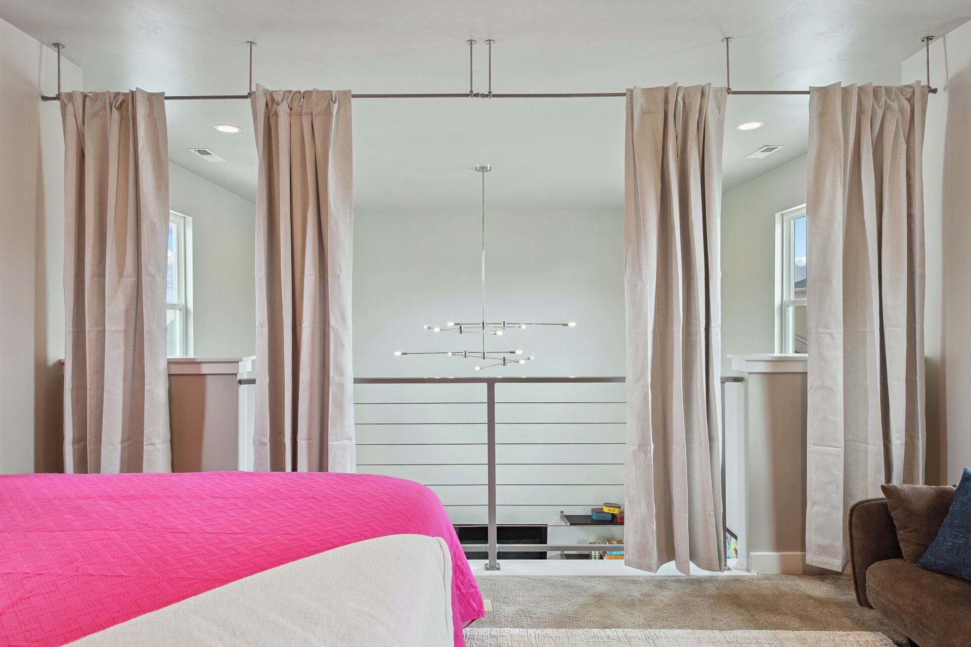 A bedroom with a bed, a hanging light fixture, and curtains.