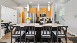 A modern kitchen with a central island, stainless steel appliances, and pendant lighting.