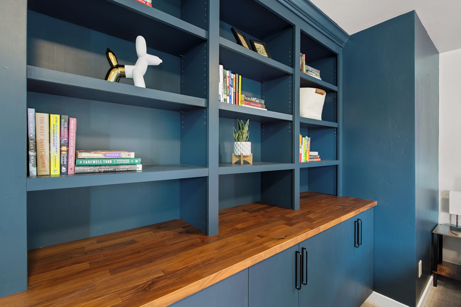 A blue bookshelf with wooden shelves and a wooden countertop.