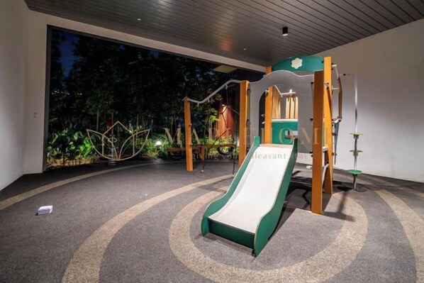 Un espace de jeux pour enfants avec un toboggan et des structures d’escalade.