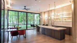 Una cucina moderna con isola centrale, ampie finestre e zona pranzo con sedie rosse.