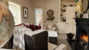 A cozy living room with a fireplace, a sofa, a coffee table, and a bookshelf.