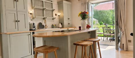 A kitchen with a central island, bar stools, and a view to the outside.