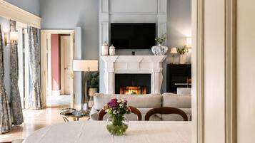 A dining room with a chandelier, a fireplace, and a television above it.