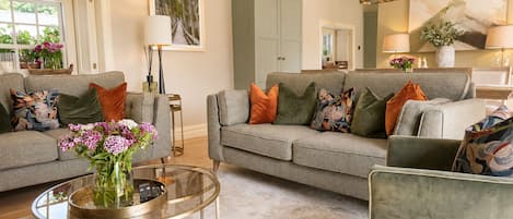 A living room with two grey sofas, a glass coffee table, and a vase with flowers.