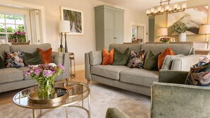 A living room with two grey sofas, a glass coffee table, and a vase with flowers.