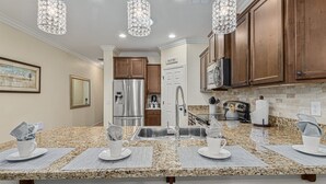 A modern kitchen with granite countertops, stainless steel appliances, and wooden cabinets. - 119th Sun City (Sun City)