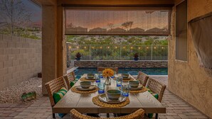 An outdoor dining area with a pool, wicker furniture, and a view of a desert landscape. - 119th Sun City (Sun City)