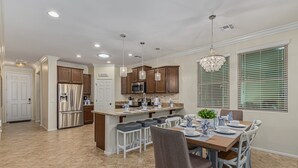 A modern kitchen with a central island, stainless steel appliances, and pendant lighting. - 119th Sun City (Sun City)