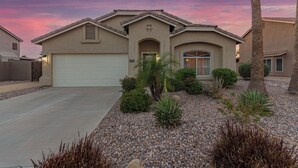 A residential house with a garage, a cross on the front, and a landscaped garden with various plants and a palm tree. - Blackfoot Two San Tan Valley (San Tan Valley)