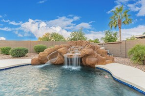 A pool with a waterfall feature surrounded by rock formations and palm trees. - Blackfoot Two San Tan Valley (San Tan Valley)