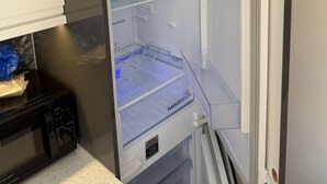 Una cocina moderna con refrigerador empotrado, microondas y encimera de acero inoxidable.