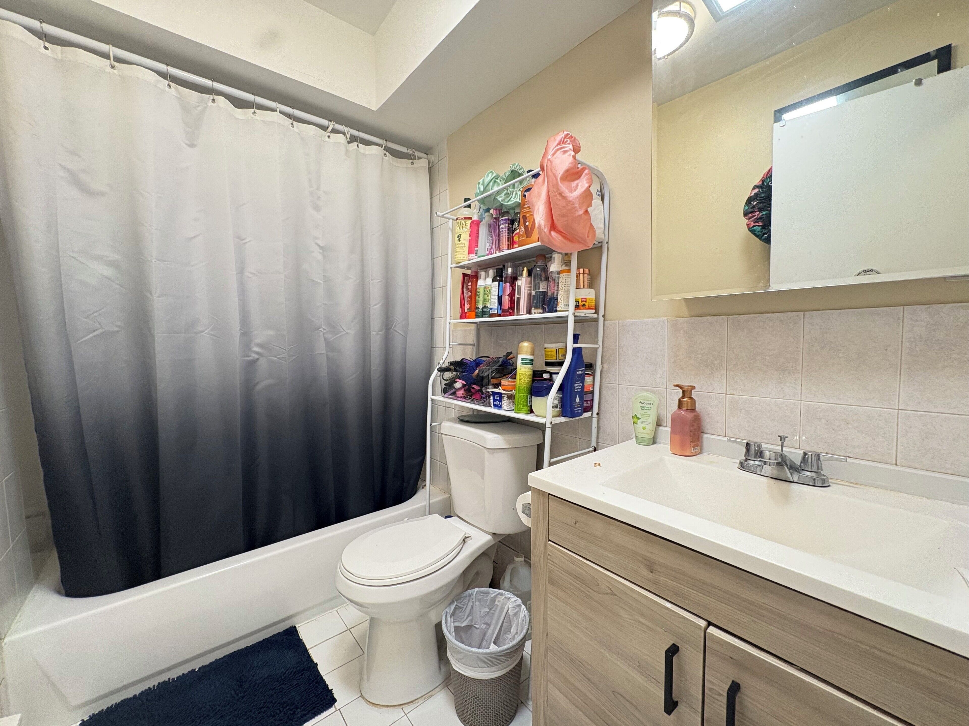 Une salle de bain avec une baignoire, des toilettes et une étagère contenant des articles de toilette.