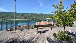 Une zone pavée avec un banc et un lampadaire, d’où l’on a vue sur une étendue d’eau et sur une ville située au loin.