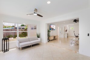 A spacious living area with a sofa, a TV, and a dining table.