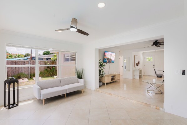 A spacious living area with a sofa, a TV, and a dining table.