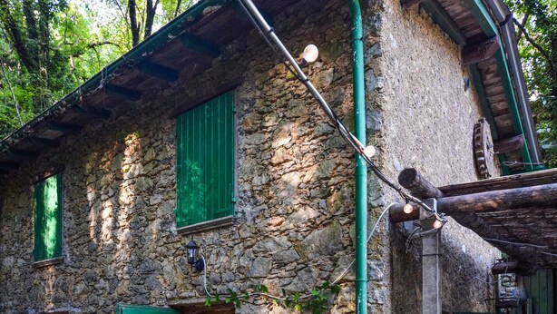 A rustic stone building with green shutters and a wooden door, featuring a stone wall and a green pipe. - 2 bedroom stunning home in Casoli (Casoli)