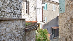 A narrow street with stone buildings, a metal railing, and a hanging light fixture.