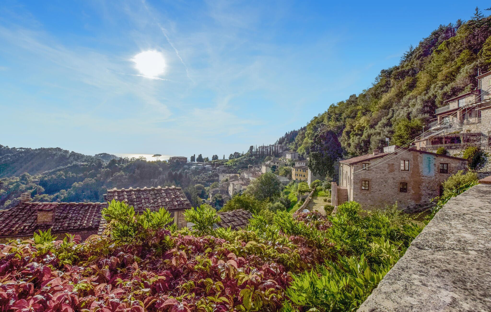 A hillside village with traditional stone buildings, terraced gardens, and a clear view of the surrounding landscape.