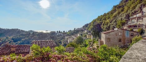 Un pueblo en una ladera con edificios de piedra tradicionales, jardines escalonados y una vista despejada del paisaje circundante.
