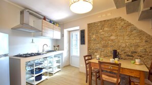 A modern kitchen with white cabinetry, a gas stove, and a stone accent wall.