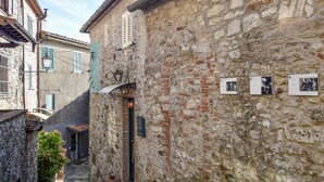 A narrow street with stone buildings, a small gate, and a potted plant.