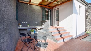 An outdoor patio with a table and chairs, a small sink, and a stone wall.