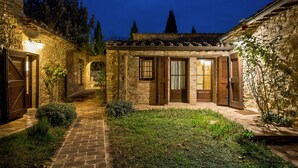 Un bâtiment en pierre avec un toit en tuiles, un chemin en briques et un petit jardin.