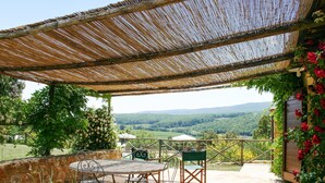 Une terrasse extérieure avec une table et des chaises, un mur en pierre et une vue sur une vallée.