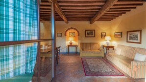 Una sala de estar acogedora con techo de madera, un sofá estampado, un tapete y un comedor con mesa y sillas.