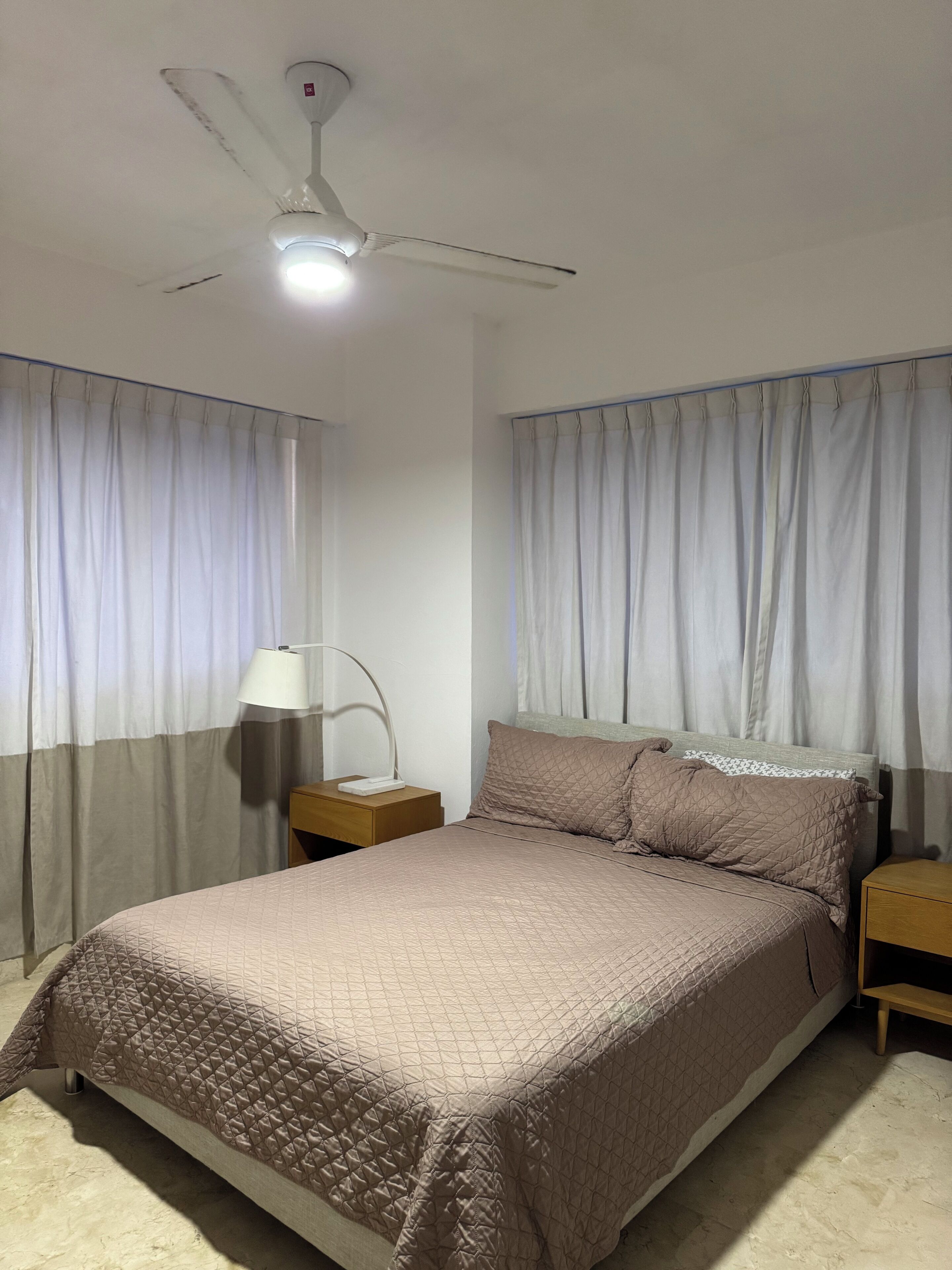 A bedroom with a bed, nightstands, a lamp, and a ceiling fan.