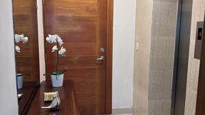 A wooden door with a mirror, a potted orchid, and a small table with a decorative item.