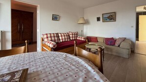 Ein gemütliches Wohnzimmer mit einer Holzsofa, einem kleineren Sofa und einem Esstisch mit kariertem Tischläufer.