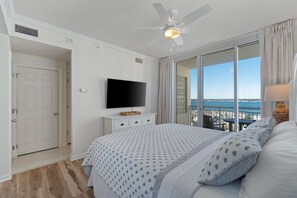 A bedroom with a large bed, a ceiling fan, a TV, and a view of the ocean. - Dog Friendly, Gulf Front Condo-Heated Pool/Hot tub (Navarre Beach)