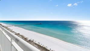 A beach with a white sandy shore, clear turquoise water, and a pier extending into the sea. - Luxurious Gulf-front Condo, Heated Pool, Spa/Gym (Navarre Beach)