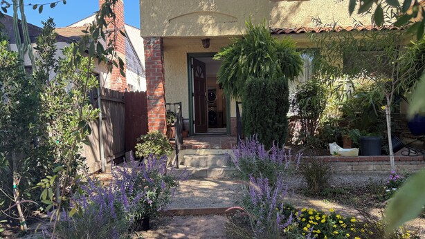 A garden pathway leading to a house with a brick exterior and a tiled roof. - Charming 1-bedroom house in Culver City (Culver City)