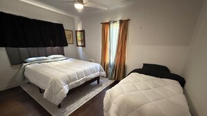 A bedroom with two beds, a ceiling fan, and a window with curtains. - Charming 1-bedroom house in Culver City (Culver City)