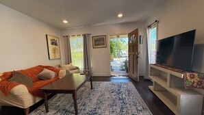 A living room with a sofa, coffee table, TV, and a view through an open door. - Charming 1-bedroom house in Culver City (Culver City)
