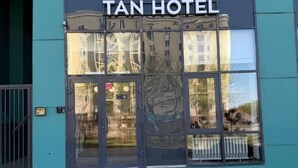 The exterior of the Tan Hotel with a modern design, featuring large glass doors and a teal facade. - Tan Hotel Astana (Astana)