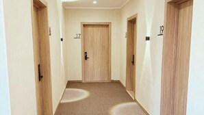 A hallway with wooden doors numbered 17 and 19, carpeted floor, and a light fixture on the ceiling. - Tan Hotel Astana (Astana)