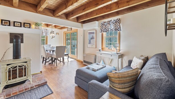 A cozy living room with a fireplace, a sofa, and a dining area with a table and chairs.